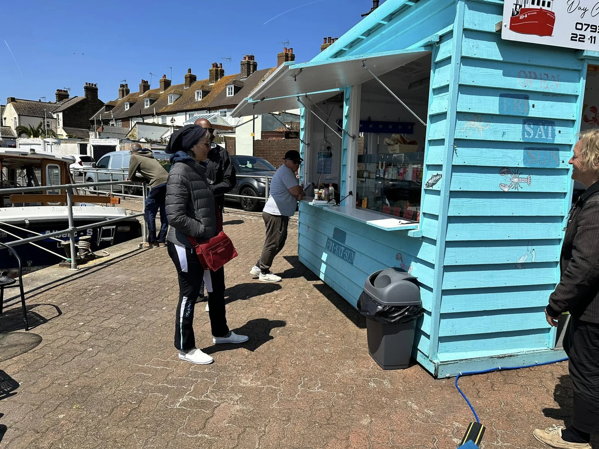 Customers visiting The Little Blue Hut beside boats in Queenborough
